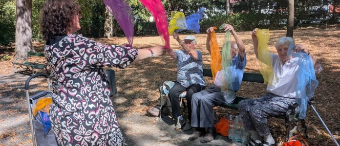 Gemeinsam in Bewegung: Beim „Tanzen im Park“ bringt Andrea McWright die Teilnehmerinnen und Teilnehmer mit Musik, bunten Tüchern und Sitztanz in Schwung. Foto: Wollschläger